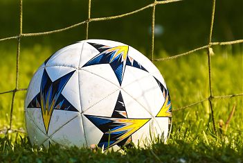 Een close-up van een voetbal in het gras voor het net van het doel